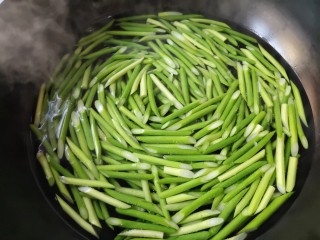 蒜苔炒腊肉,把切好的蒜台放入锅内过一下，这样蒜台就能入味了。