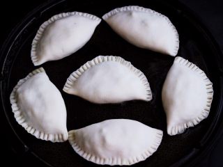 百吃不厌的韭菜盒子,电饼铛提前预热后，用硅胶勺子蘸少许食用油把电饼铛的锅底刷匀后，把包好的韭菜盒子放入锅中。