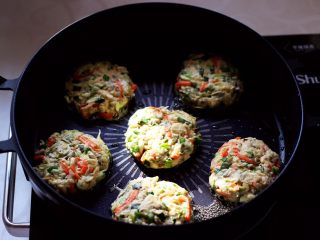 槐花胡萝卜鸡蛋饼,把做好的槐花饼平铺在锅里。