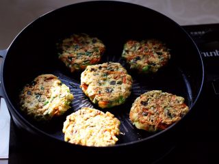 槐花胡萝卜鸡蛋饼,把槐花饼的一面煎至金黄色后，再翻面煎至另一面。