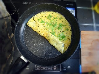 青椒虾皮鸡蛋卷,鸡蛋底部煎至金黄时，关火将鸡蛋饼卷起。