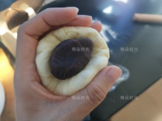 豆沙面包卷,取一个面团，稍微擀开，包入豆沙馅。捏紧收口。然后滚圆。