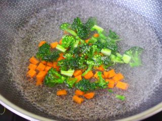 西兰花猪肝粥（宝宝辅食）,锅中倒入适量的清水烧开后，加入少许盐和几滴食用油，把胡萝卜和西兰花进行焯水1分钟后，捞出沥干水分备用。