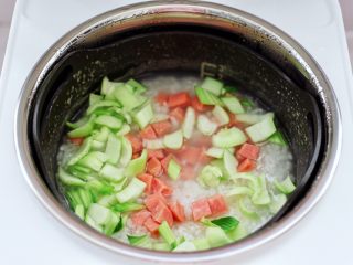 青口火腿青菜粥,烹饪至40分钟的时候，打开锅盖，锅中米粥已浓稠软烂了，这个时候先加入火腿丁和青菜的茎，盖上锅盖继续煮5分钟。